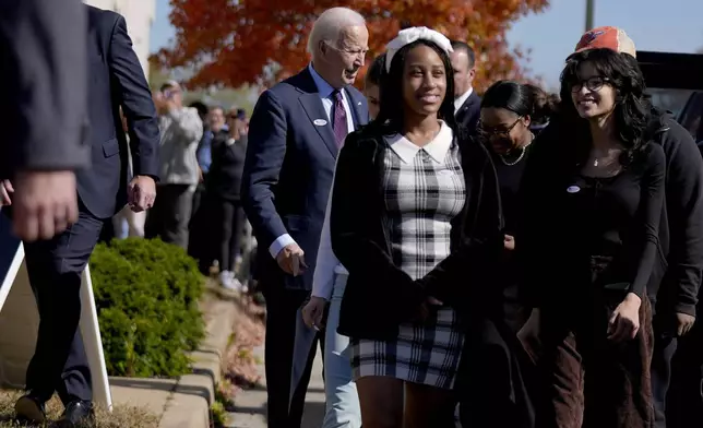 President Joe Biden, left, departs a polling station alongside first-time voters after casting his early-voting ballot for the 2024 general elections, Monday, Oct. 28, 2024, in New Castle, Del. (AP Photo/Manuel Balce Ceneta)