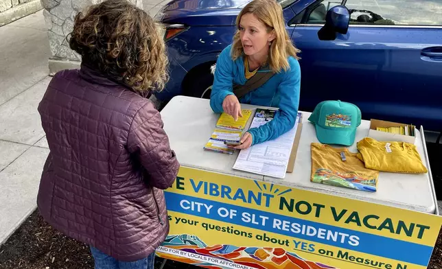 Amelia Richmond, Co-Founder, Locals for Affordable Housing, talks to a voter outside a grocery store in South Lake Tahoe, Calif. on Thursday, Oct. 17, 2024, where voters will decide whether to approve Measure N, which will mandate a tax to homeowners who leave their homes vacant for more than half the year.v(AP Photo/Haven Daley)