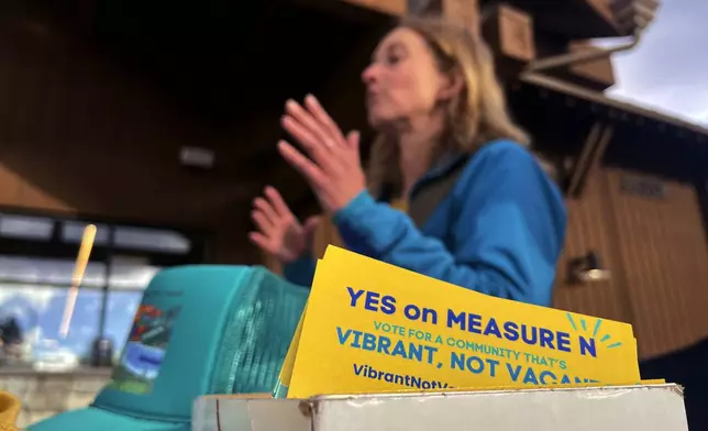 Amelia Richmond, Co-Founder, Locals for Affordable Housing, talks to a voter outside a grocery store in South Lake Tahoe, Calif. on Thursday, Oct. 17, 2024, where voters will decide whether to approve Measure N, which will mandate a tax to homeowners who leave their homes vacant for more than half the year.v(AP Photo/Haven Daley)