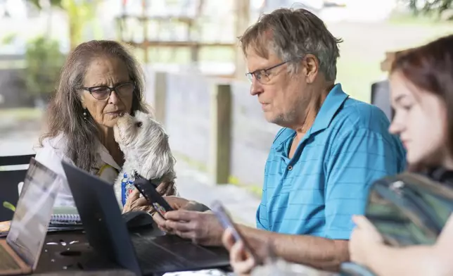 Patricia Sepulveda and Keith Fieldhammer send texts at IX Art Park in Charlottesville, Va., Thursday, Oct. 10, 2024. Charlottesville Democrats meet weekly to make phone calls, write postcards and send texts to get out the vote. (AP Photo/Ryan M. Kelly)