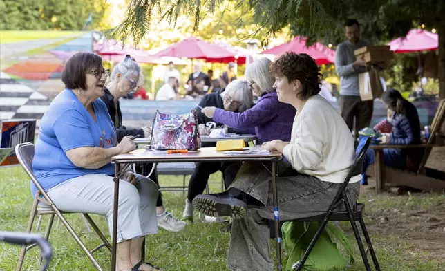 Nancy Gulotta and Cannon Slayton write postcards at IX Art Park in Charlottesville, Va., Thursday, Oct. 10, 2024. Charlottesville Democrats meet weekly to make phone calls, write postcards and send texts to get out the vote. (AP Photo/Ryan M. Kelly)