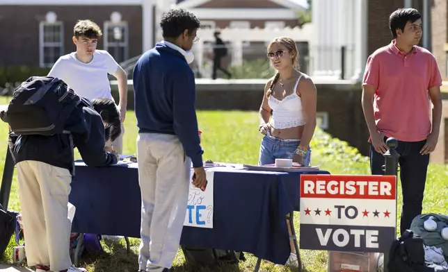 James Galvin, Charlotte Papacosma and Kushaan Soodan register students to vote at the University of Virginia in Charlottesville, Va., Friday, Oct. 11, 2024. (AP Photo/Ryan M. Kelly)