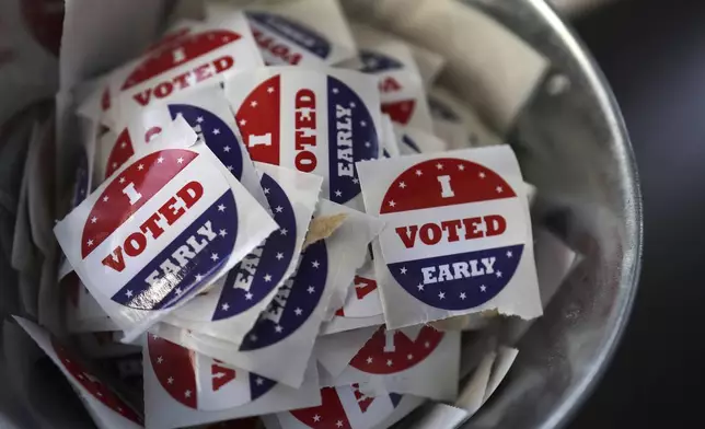 FILE "- I Voted Early" stickers sit in a bucket by the ballot box at the City of Minneapolis early voting center, Thursday, Sept. 19, 2024, in St. Paul, Minn. (AP Photo/Adam Bettcher, File)