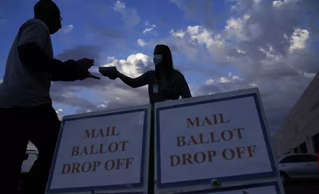 FILE - A county worker collects a mail-in ballots in a drive-thru mail-in ballot drop off area at the Clark County Election Department, Monday, Nov. 2, 2020, in Las Vegas. (AP Photo/John Locher, File)