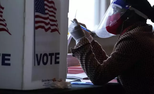 FILE - A poll worker talks to a voter before they vote on a paper ballot on Election Day in Atlanta on Tuesday, Nov. 3, 2020. (AP Photo/Brynn Anderson, File)