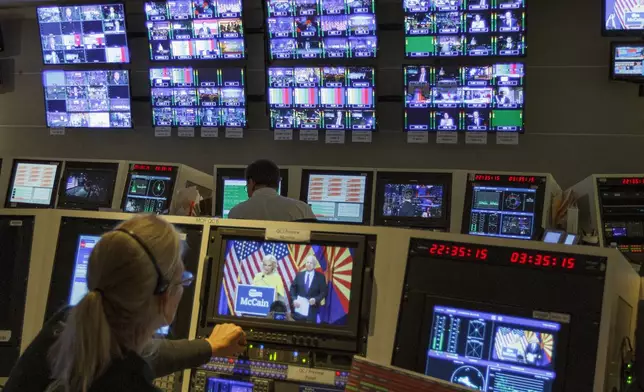 FILE - Staff members of The Associated Press Television Network work in master control at the Washington bureau of The Associated Press in Washington, Nov. 8, 2016, as returns come in during election night. (AP Photo/Jon Elswick)