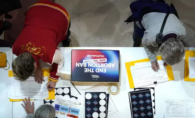 FILE - Residents place their signatures on a petition in support of a ballot initiative to end Missouri's near-total ban on abortion during Missourians for Constitutionals Freedom kick-off petition drive, Feb. 6, 2024, in Kansas City, Mo. (AP Photo/Ed Zurga, File)