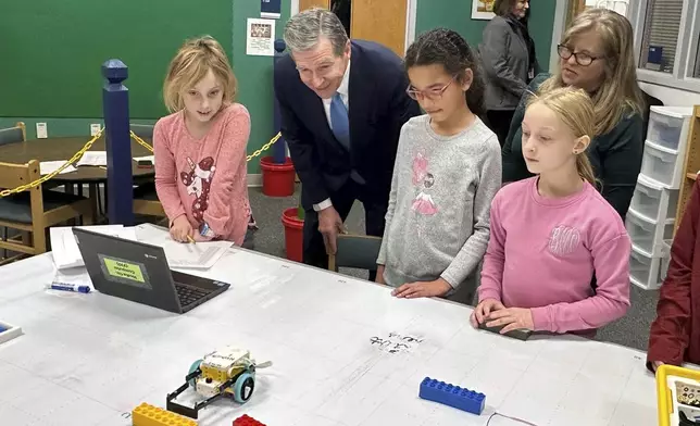 FILE - North Carolina Gov. Roy Cooper, center left, watches a robotics team at Nashville Elementary School in Nashville, N.C., direct its vehicle in the school library, Tuesday, Jan. 23, 2024. (AP Photo/Gary D. Robertson, File)