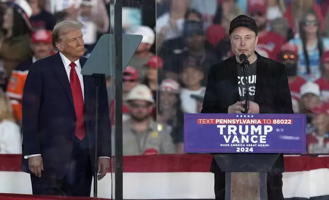 FILE - Republican presidential nominee former President Donald Trump listens as Elon Musk speaks during a campaign rally at the Butler Farm Show, Saturday, Oct. 5, 2024, in Butler, Pa. (AP Photo/Julia Demaree Nikhinson, File)