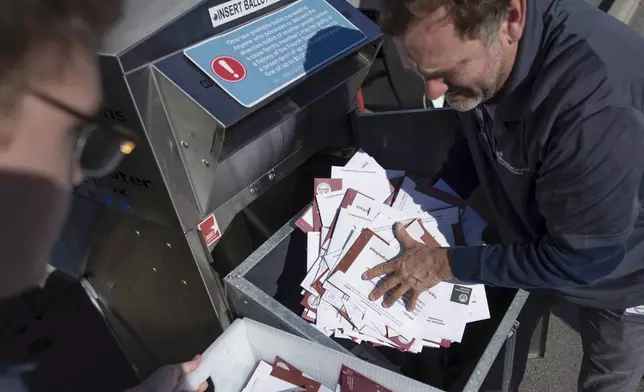 FILE - Seth Golding, right, and Braydon Galliers, left, a bipartisan team of ballot fulfillment coordinators, empty an absentee voter drop-off ballot box on Election Day outside of the Franklin County Board of Elections in Columbus, Ohio, Tuesday, Nov. 7, 2023. (AP Photo/Carolyn Kaster, File)