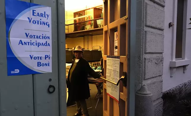 A poll worker opens the door at a precinct on the first day of early voting in the general election Monday, Oct. 21, 2024, in Miami. (AP Photo/Lynne Sladky)