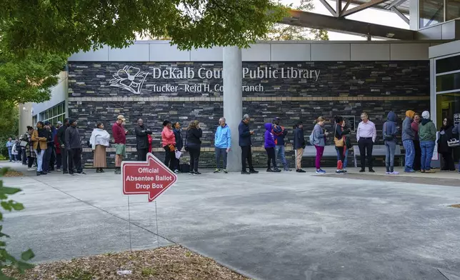 People line up around the building at the Tucker-Reid H. Cofer branch of the Dekalb County Public Library on the first day of early voting, Tuesday, Oct. 15, 2024 in Tucker, Ga. (Matthew Pearson/WABE via AP)