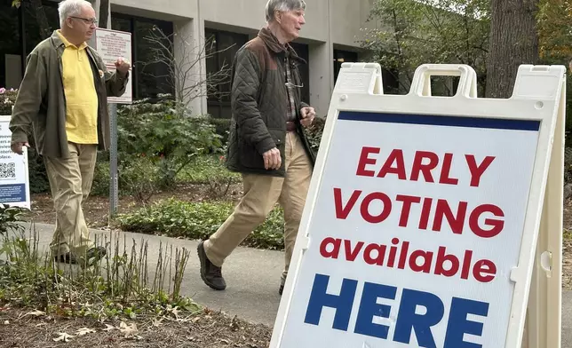 People leave after voting in the Atlanta suburb of Sandy Springs, Ga., on Tuesday, Oct. 15, 2024, the first day of early in-person voting in Georgia. (AP Photo/Jeff Amy)