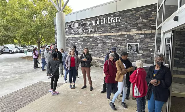 People line up to vote in the Atlanta suburb of Tucker, Ga., on Tuesday, Oct. 15, 2024, the first day of early in-person voting in Georgia. (AP Photo/Jeff Amy)