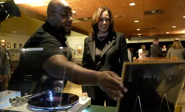 Ishmael Trainor, owner of Legenderie Records and Coffee House, left, shows Democratic presidential nominee Vice President Kamala Harris a Marvin Gaye record during a campaign stop at the Black-owned small business, Monday, Oct. 14, 2024, in Erie, Pa. (AP Photo/Jacquelyn Martin)