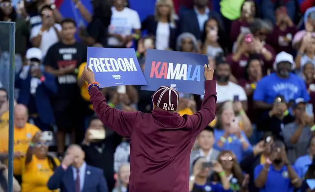 Spike Lee holds signs while on stage at a campaign rally supporting Democratic presidential nominee Vice President Kamala Harris, Thursday, Oct. 24, 2024, in Clarkston, Ga. (AP Photo/Mike Stewart)