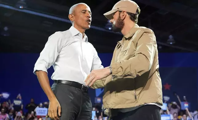 Rapper Eminem, right, greets former President Barack Obama, left, on stage at a campaign rally supporting Democratic presidential nominee Vice President Kamala Harris, Tuesday, Oct. 22, 2024, in Detroit. (AP Photo/Paul Sancya)