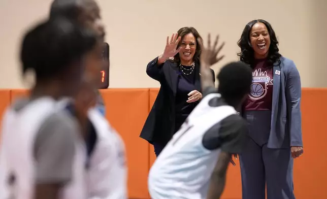 Democratic presidential nominee Vice President Kamala Harris waves to a player alongside coach Randyll Butler as they watch a youth basketball practice before a community rally at the Alan Horwitz "Sixth Man" Center, Sunday, Oct. 27, 2024, in Philadelphia. (AP Photo/Susan Walsh)