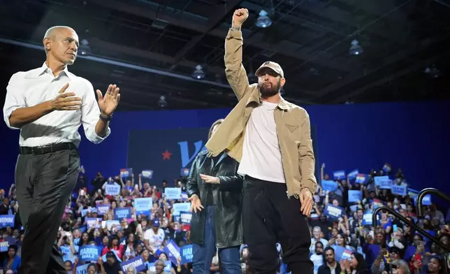 Rapper Eminem, center, greets the crowd on stage with former President Barack Obama, left, at a campaign rally supporting Democratic presidential nominee Vice President Kamala Harris, Tuesday, Oct. 22, 2024, in Detroit. (AP Photo/Paul Sancya)