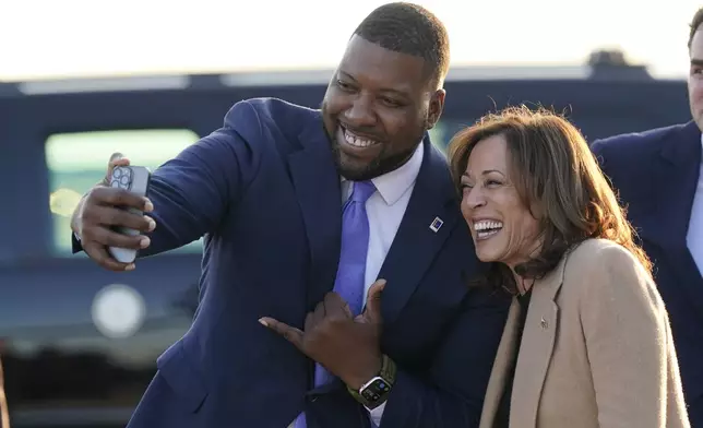 Durham, N.C. Mayor Leonardo Williams, left, takes a selfie with Democratic presidential nominee Vice President Kamala Harris as she arrives at Raleigh-Durham International Airport in Morrisville, N.C., Saturday, Oct. 12, 2024. (AP Photo/Steve Helber)