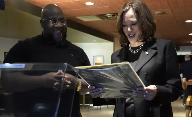 Ishmael Trainor, owner of Legenderie Records and Coffee House, left, shows Democratic presidential nominee Vice President Kamala Harris a Marvin Gaye record during a campaign stop at the Black-owned small business, Monday, Oct. 14, 2024, in Erie, Pa. (AP Photo/Jacquelyn Martin)