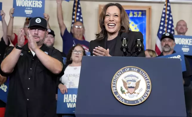 Democratic presidential nominee Vice President Kamala Harris speaks as Benjamin Frantz, left, president of UAW Local 652, looks on at UAW Local 652 during a campaign event in Lansing, Mich., Friday, Oct. 18, 2024. (AP Photo/Jacquelyn Martin)