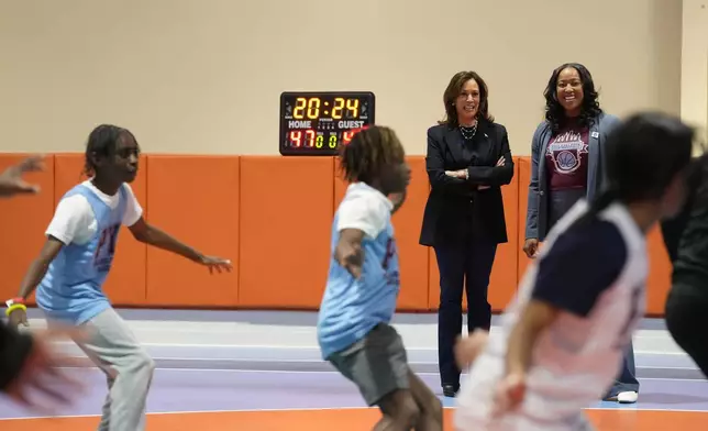 Democratic presidential nominee Vice President Kamala Harris, standing at left, and coach Randyll Butler, watch as young basketball players practice before a community rally at the Alan Horwitz "Sixth Man" Center, Sunday, Oct. 27, 2024, in Philadelphia. (AP Photo/Susan Walsh)