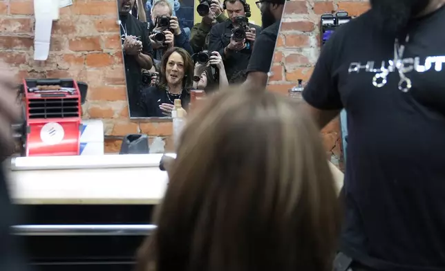 Democratic presidential nominee Vice President Kamala Harris sits in the "lucky chair" while photographers take her photo at Philly Cuts barbershop during a campaign stop, Sunday, Oct. 27, 2024, in Philadelphia. (AP Photo/Susan Walsh)