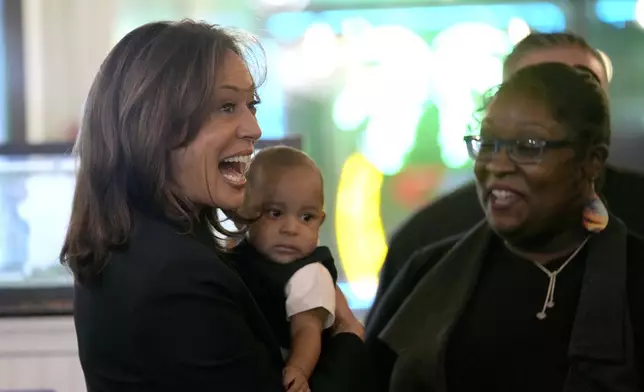 Democratic presidential nominee Vice President Kamala Harris, left, greets guests while holding a baby at Freddy and Tony's restaurant during a campaign stop, Sunday, Oct. 27, 2024, in Philadelphia. (AP Photo/Susan Walsh)