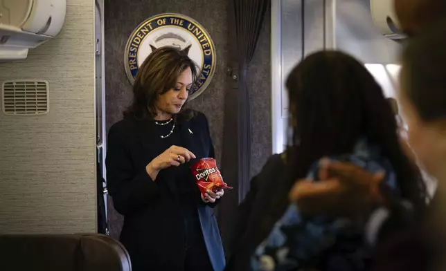 Democratic presidential nominee Vice President Kamala Harris eats Doritos and thanks senior staff aboard Air Force Two in Philadelphia, Sunday, Oct. 27, 2024. (Erin Schaff//The New York Times via AP, Pool)