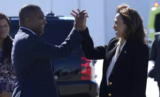 Democratic presidential nominee Vice President Kamala Harris, right, high-fives Rep. Don Davis, D-N.C., as she arrives at Pitt-Greenville Airport in Greenville, N.C., Sunday, Oct. 13, 2024, to speak at a campaign rally. (AP Photo/Susan Walsh)