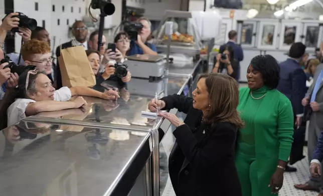 Democratic presidential nominee Vice President Kamala Harris, with Philadelphia Mayor Cherelle Parker, right, signs an autograph and speaks to workers and patrons at a campaign stop at Famous 4th Street Delicatessen in Philadelphia, Wednesday, Oct. 23, 2024. (AP Photo/Matt Rourke)