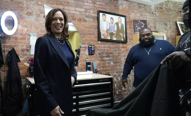 Democratic presidential nominee Vice President Kamala Harris, left, walks to sit in the "lucky chair" at Philly Cuts barbershop during a campaign stop, Sunday, Oct. 27, 2024, in Philadelphia. (AP Photo/Susan Walsh)