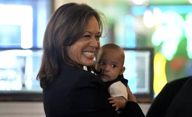 Democratic presidential nominee Vice President Kamala Harris, left, holds a baby as she greets guests at Freddy and Tony's restaurant during a campaign stop, Sunday, Oct. 27, 2024, in Philadelphia. (AP Photo/Susan Walsh)