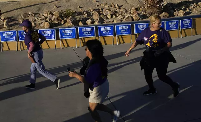 People rush to to attend a rally with former President Barack Obama speaking in support of Democratic presidential nominee Vice President Kamala Harris, Saturday, Oct. 19, 2024, in North Las Vegas, Nev. (AP Photo/John Locher)