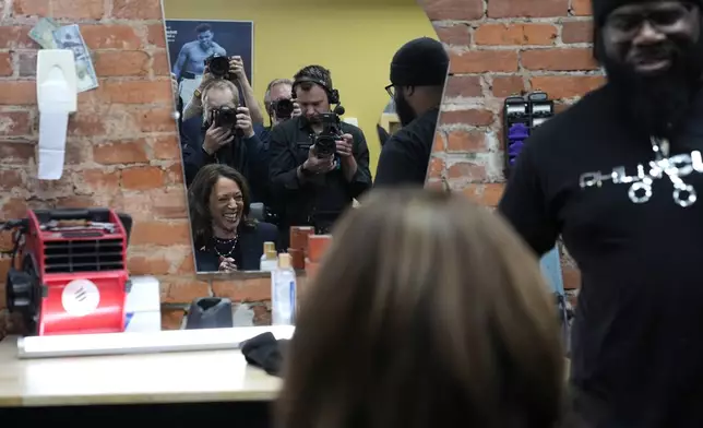 Democratic presidential nominee Vice President Kamala Harris sits in the "lucky chair" while photographers take her photo at Philly Cuts barbershop during a campaign stop, Sunday, Oct. 27, 2024, in Philadelphia. (AP Photo/Susan Walsh)