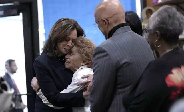 Democratic presidential nominee Vice President Kamala Harris, from left, hugs Ann Hughes as her son State Sen. Vincent Hughes, D-Philadelphia, looks on at Hakim's Bookstore and Gift Shop during a campaign stop, Sunday, Oct. 27, 2024, in Philadelphia. (AP Photo/Susan Walsh)