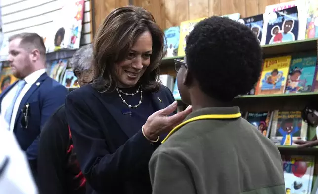 Democratic presidential nominee Vice President Kamala Harris, left, greets a young man at Hakim's Bookstore and Gift Shop during a campaign stop, Sunday, Oct. 27, 2024, in Philadelphia. (AP Photo/Susan Walsh)