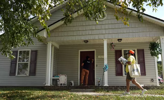 Salvador Fonseca knocks on a door with Elena Jimenez as they visit a home during a voter engagement event for the Latino community in Greensboro, N.C., Saturday, Sept. 21, 2024. (AP Photo/Chuck Burton)