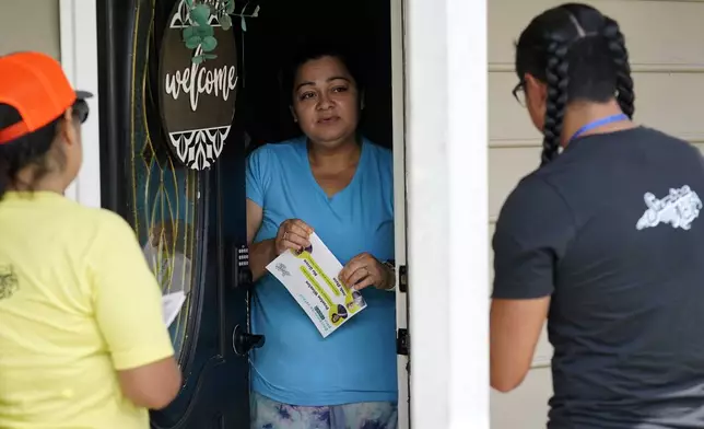 Salvador Fonseca, right, and Elena Jimenez, left, speak with Johanna Ortiz during a voter engagement event for the Latino community in Greensboro, N.C., Saturday, Sept. 21, 2024. (AP Photo/Chuck Burton)