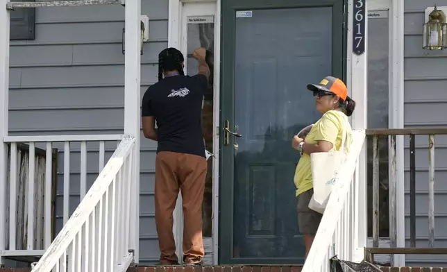 Salvador Fonseca, left, and Elena Jimenez knock on the door of a home during a voter engagement event for the Latino community in Greensboro, N.C., Saturday, Sept. 21, 2024. (AP Photo/Chuck Burton)