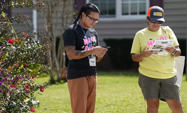 Salvador Fonseca, left, and Elena Jimenez take notes after visiting a home during a voter engagement event for the Latino community in Greensboro, N.C., Saturday, Sept. 21, 2024. (AP Photo/Chuck Burton)