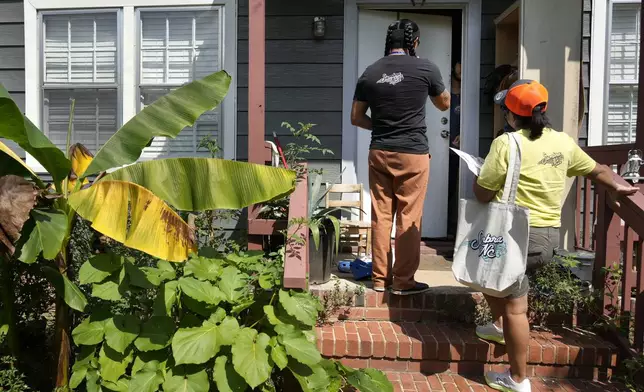 Salvador Fonseca, left, and Elena Jimenez talk to a homeowner during a voter engagement event for the Latino community in Greensboro, N.C., Saturday, Sept. 21, 2024. (AP Photo/Chuck Burton)