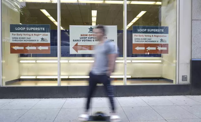 A person skateboards past a sign for early voting for the 2024 Presidential General Election, Thursday, Oct. 3, 2024 in Chicago. (AP Photo/Charles Rex Arbogast)