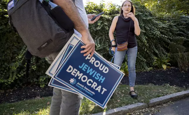 Dan Vogl, a doctor from Bala Cynwyd, left, talks to Chris Dorian as he goes door to door to canvass Jewish voters during the Jewish holiday of Sukkot in Bala Cynwyd, Pa., Sunday, Oct. 20, 2024. (AP Photo/Laurence Kesterson)