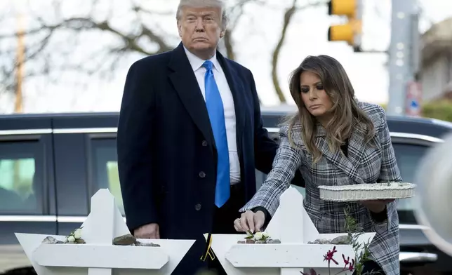 FILE - First lady Melania Trump, accompanied by President Donald Trump, puts down a white flower at a memorial for those killed at the Tree of Life Synagogue in Pittsburgh, Oct. 30, 2018. (AP Photo/Andrew Harnik, File)