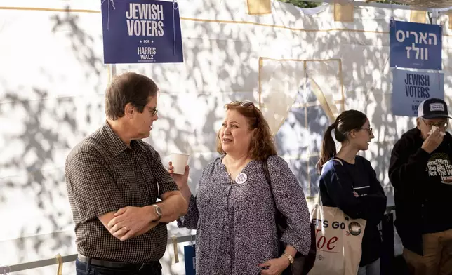 Mark and Suzan Lopatin gather with other supportes of Democratic presidential nominee Vice President Kamala Harris in a Sukkot before going door to door to canvass Jewish voters Sunday, Oct. 20, 2024. (AP Photo/Laurence Kesterson)