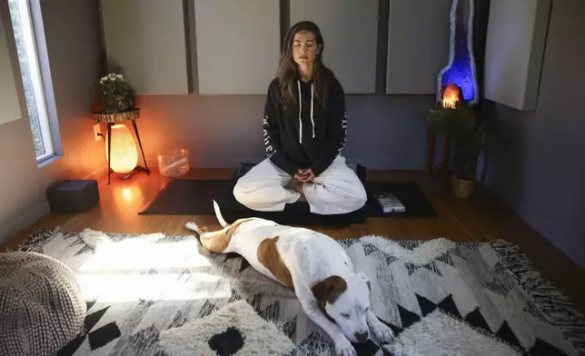 Headspace meditation teacher, Rosie Acosta, meditates in her studio with her dog Monday, Sept. 30, 2024, in Woodland Hills, Calif. (AP Photo/Jessie Alcheh)