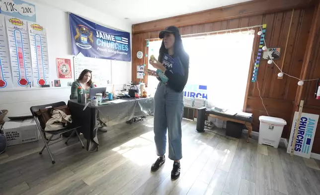 Democratic state Rep. Jaime Churches looks over her phone before going door to door to campaign, Friday, Oct. 11, 2024, in Trenton, Mich. (AP Photo/Carlos Osorio)