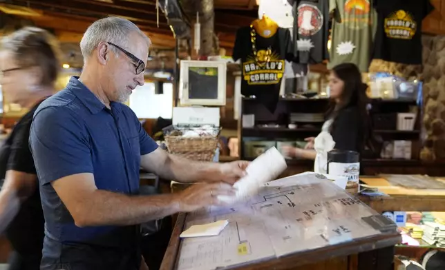 Dan Piacquadio, owner of Harold's Cave Creek Corral, checks for reservations at the entrance of the restaurant as he waits for the upcoming election regarding Arizona Prop 138 on minimum wage Thursday, Oct. 3, 2024, in Cave Creek, Ariz. (AP Photo/Ross D. Franklin)